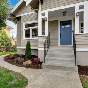 Front steps and concrete pathway to blue door and porch
