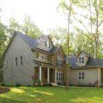 Home in woods with brick and tan siding