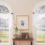 Matching arching windows looking out into trees.