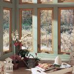 Large vertical windows in living room looking at woods